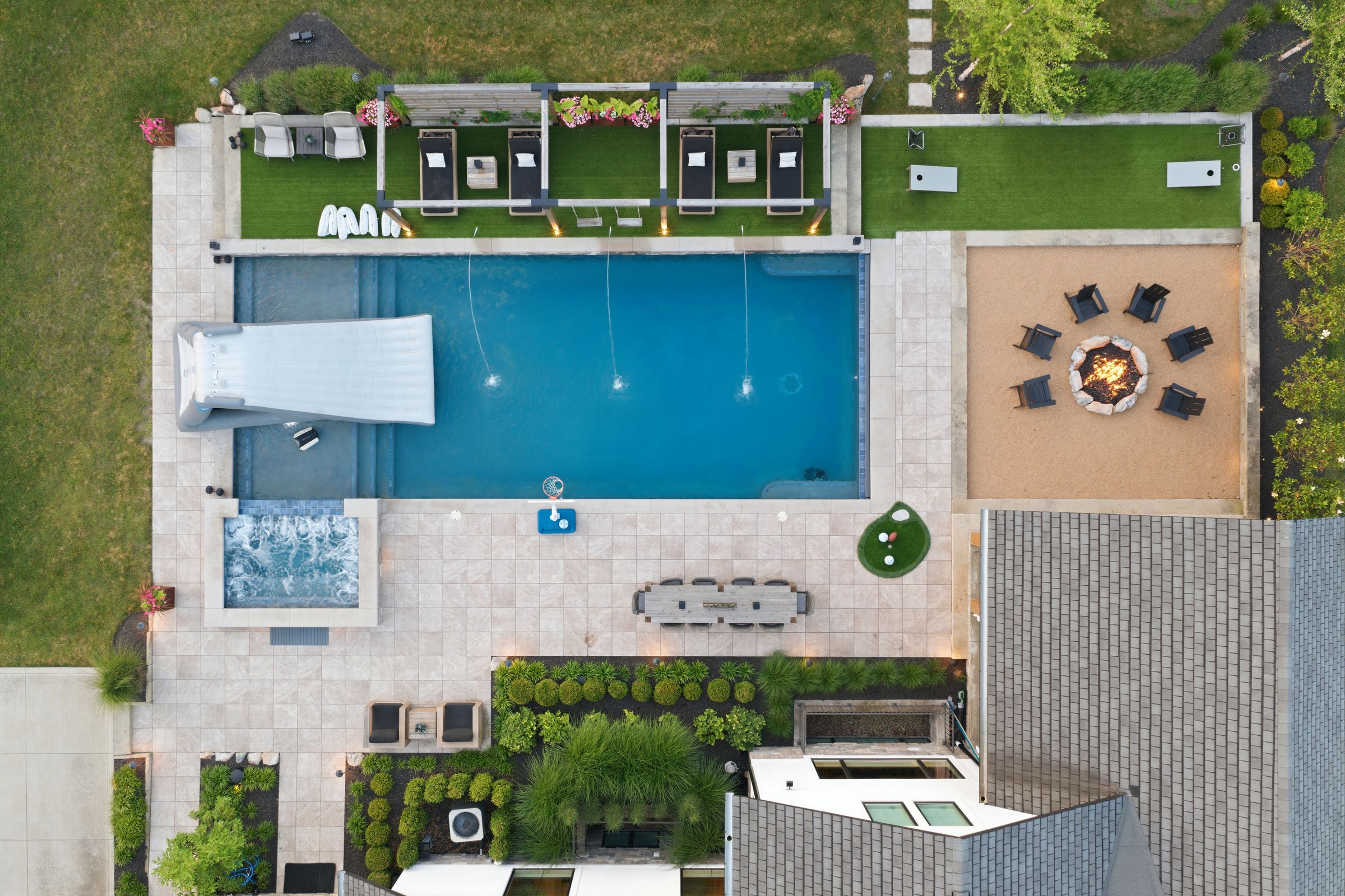 Overhead dusk view of the pool, spa, cabanas, putting green and lit fire pit